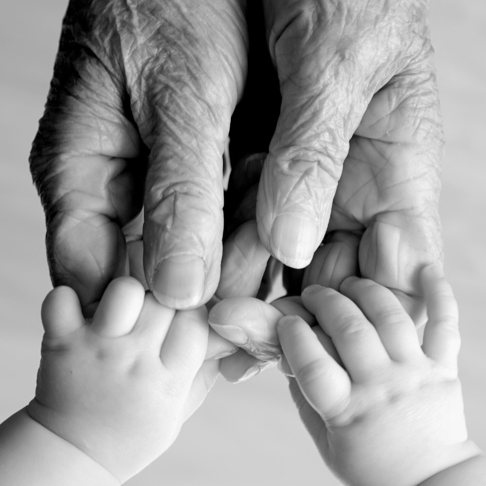 Gamla händer håller i babyhänder